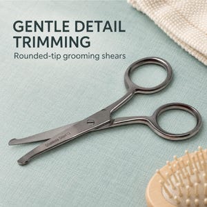 May include: Stainless steel grooming shears with rounded tips and finger loops. The metal blades are engraved with the text "Stainless Steel CE". The text "GENTLE DETAIL TRIMMING" and "Rounded-tip grooming shears" appear in the image.