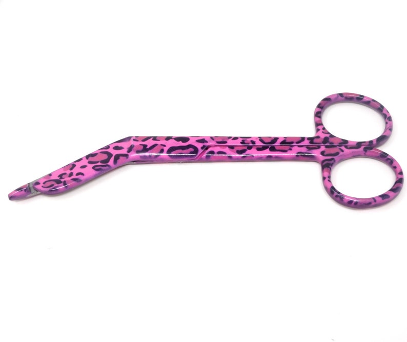 May include: Pink surgical scissors with a leopard print design. The scissors have a curved handle and sharp blades.