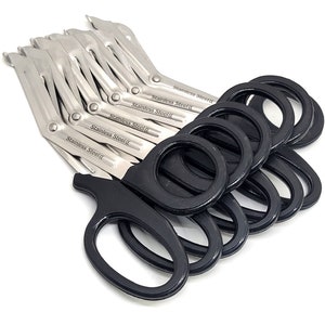 May include: A set of ten black-handled stainless steel bandage scissors. The scissors are stacked on top of each other, with the handles facing up. The blades are closed and the handles are made of black plastic.
