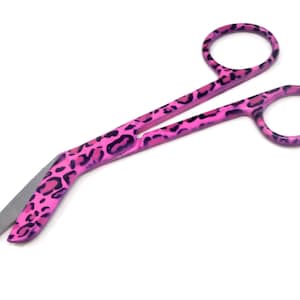 May include: Pink bandage scissors with a leopard print design.