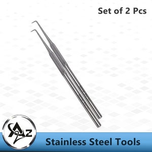 May include: Set of two stainless steel tools with a pointed tip. The tools are silver in color and have a textured handle. The text "German Stainless" is printed on the tools. The tools are labeled "Set of 2 Pcs" and "Stainless Steel Tools".