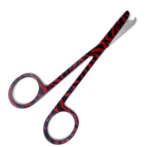 Puede incluir: Tijeras para cutículas de acero inoxidable con estampado rojo y negro con punta afilada.