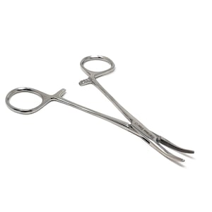 Puede incluir: Un hemostático de acero inoxidable con una punta curva y un mecanismo de bloqueo. El hemostático es un instrumento médico que se utiliza para sujetar los vasos sanguíneos.