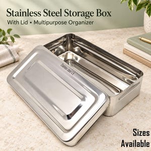 May include: A rectangular stainless steel storage box with a matching lid. The lid features the text Stainless steel CE. The container has a polished metallic finish, rounded corners, and a deep interior cavity for multipurpose organization.
