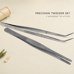 Könnte beinhalten: Ein Präzisionspinzetten-Set bestehend aus zwei silberfarbenen Edelstahlpinzetten mit unterschiedlichen Spitzenformen. Eine Pinzette hat eine gerade Spitze, die andere eine abgewinkelte Spitze. Der Text lautet: PRECISION TWEEZER SET 2 DIFFERENT TIP STYLES.