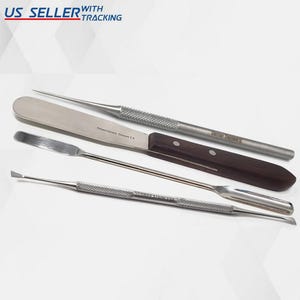 May include: Set of four stainless steel tools for crafting and hobby projects. The set includes a spatula with a wooden handle, a small spatula, a pointed tool, and a tool with a small scoop. The tools are all made of stainless steel and have a brushed finish.
