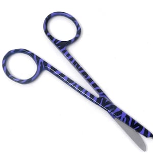 Op de afbeelding: Paarse en zwarte chirurgische schaar met zebraprint en een zilveren mes.