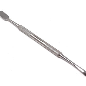 Puede incluir: Una herramienta de raspado de acero inoxidable con una cuchilla curva y un mango texturizado. La herramienta está etiquetada como "STAINLESS-CE-PRO".