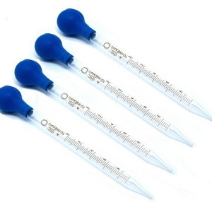 May include: Four clear glass pipettes with blue rubber bulbs. Each pipette is marked with graduated measurements in milliliters. The pipettes are designed for precise liquid transfer in a laboratory or scientific setting.