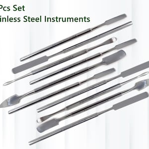 May include: A set of 10 stainless steel instruments, including spatulas, scrapers, and a pointed tool. The tools are arranged in a fan shape on a white background.