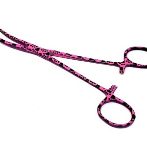 Puede incluir: Pinza hemostática rosa con diseño de huella de pata negra.