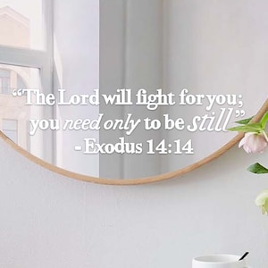 Puede incluir: Un espejo redondo con marco de madera refleja una cita de Éxodo 14:14, "El Señor peleará por ti; tú solo tienes que estar tranquilo."