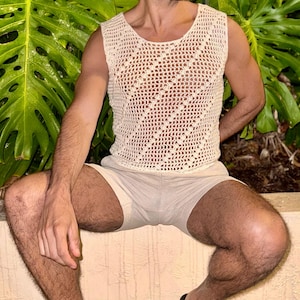 May include: A white crocheted tank top with a diamond pattern. The tank top is sleeveless and has a scoop neck.