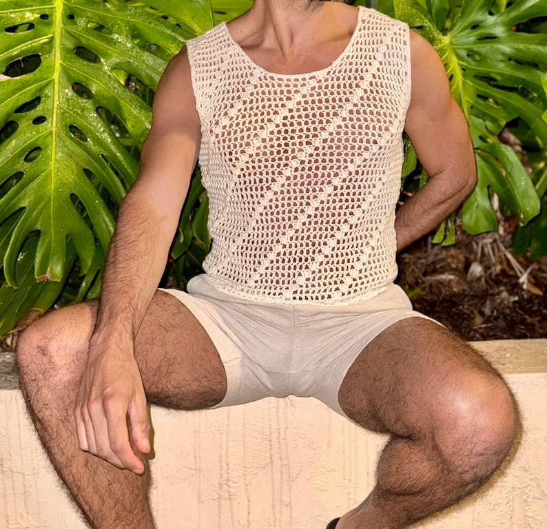 May include: A white crocheted tank top with a diamond pattern. The tank top is sleeveless and has a scoop neck.