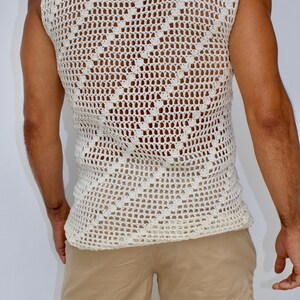 May include: A white crocheted sleeveless top with a diamond pattern. The top is loose fitting and has a scoop neck.