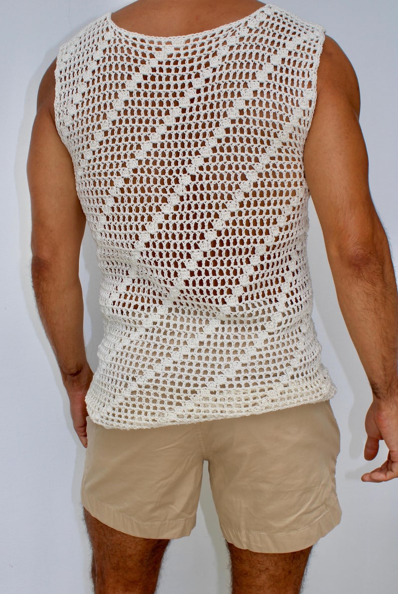 May include: A white crocheted sleeveless top with a diamond pattern. The top is loose fitting and has a scoop neck.