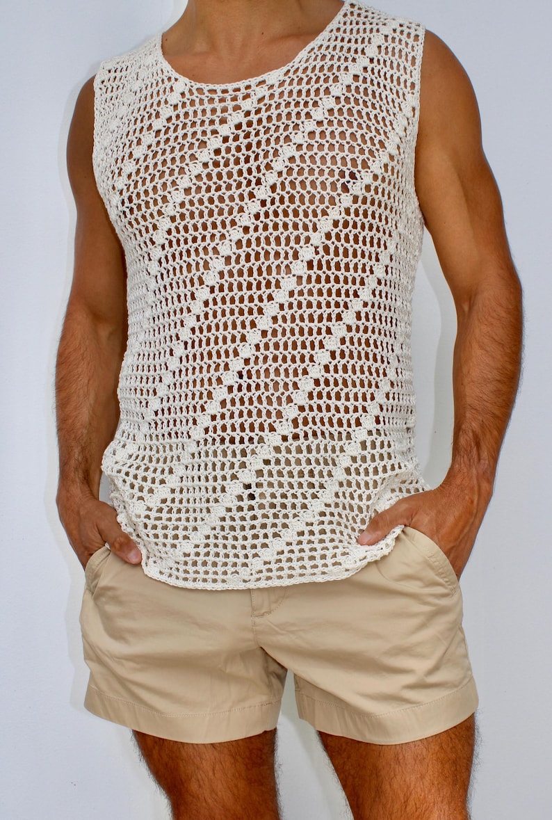 May include: A white crocheted sleeveless shirt with a diamond pattern. The shirt is worn over a pair of beige shorts.