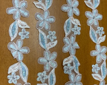Pode incluir: Bordado floral azul claro com lantejoulas e contas. O bordado é feito de um tecido transparente e tem um visual delicado e feminino.