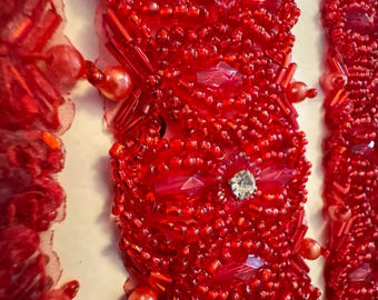 Pode incluir: Trimming de contas vermelhas com strass transparentes. O trimming é feito de contas pequenas e redondas e tem um padrão repetitivo.