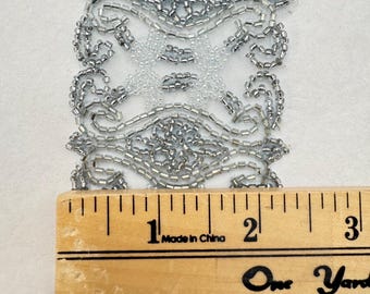 May include: Silver beaded trim with a repeating pattern. The trim is approximately 2.5 cm wide and is measured against a ruler that reads "Made in China".