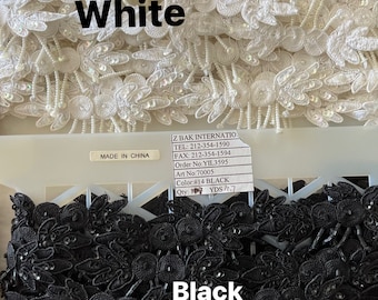 Pode incluir: Close-up de duas filas de guarnição de contas pretas e brancas. A guarnição é feita de pequenas flores delicadas com um centro de contas. A fila superior é branca e a fila inferior é preta. A guarnição é etiquetada como "Branco" e "Preto" com o nome da empresa e as informações de contato.