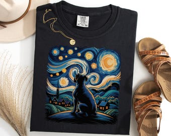 Puede incluir: Camiseta negra con la silueta de un perro sobre un diseño de cielo nocturno arremolinado en azul, amarillo y blanco. La camiseta incluye la etiqueta Comfort Colors XL-TG. También se ven un collar dorado y sandalias marrones.