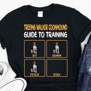 Könnte beinhalten: Schwarzes T-Shirt mit gelbem Text, der "Treeing Walker Coonhound Guide to Training" lautet. Vier gelbe Kästchen mit schwarzen Umrandungen enthalten Bilder eines Hundes und die Wörter "Sit", "Down", "Fetch" und "Stay".