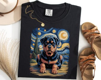 Puede incluir: Camiseta negra con una ilustración de perro Rottweiler al estilo de "La noche estrellada" de Van Gogh. El perro es negro y marrón, sobre un fondo arremolinado azul y amarillo. La camiseta tiene cuello redondo y etiqueta Comfort Colors.