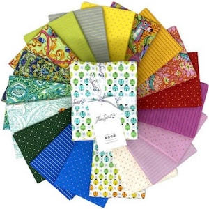 May include: A collection of 18 fabric squares in various colors and patterns, including floral, geometric, and striped designs. The fabric squares are arranged in a fan shape and feature a label that reads "Free Spirit".