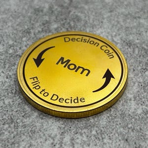 May include: A gold-colored coin with the words "Decision Coin" and "Flip to Decide" on it. The word "Mom" is in the center of the coin.