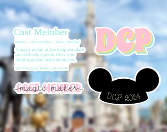 May include: A pink and blue sticker with the text "DCP" in a bold, outlined font. Below the sticker is a black Mickey Mouse ear hat sticker with the text "DCP 2024" in white. The stickers are on a blurred background of a castle.