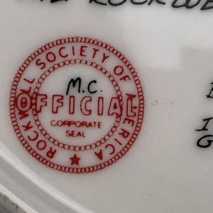 May include: Red and white circular seal with the text "Rockwell Society of America" and "M.C. Official Corporate Seal" inside. The seal has a star in the center.