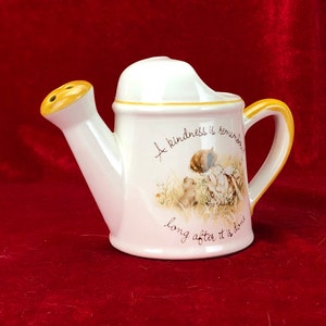 Pode incluir: Regador de cer&acirc;mica branca com um bico e uma al&ccedil;a amarelos. Tem um design floral e o texto "A kindness is remembered long after it is done".
