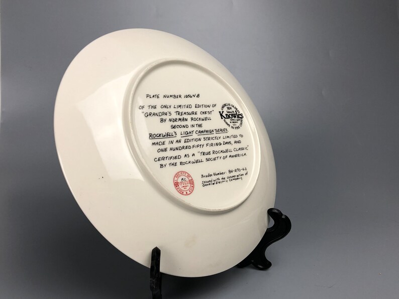 May include: White ceramic plate with a black and white image of a plate with the text "Plate Number 184/8 of the only limited edition of "Grandpa's Treasure Chest" by Norman Rockwell. Second in the Rockwell's Light Campaign Series. Made in an edition strictly limited to one hundred fifty firing days, and certified as a True Rockwell Classic by the Rockwell Society of America." The plate also has a red seal with the text "Brader Number 86/170-63 Issued with the cooperation of General Electric Company."