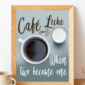 May include: A framed print with a blue background featuring a cup of coffee and a small glass of milk. The text "Cafe con Leche" is written in cursive at the top of the print. Below the coffee and milk, the text "When two become one" is written in cursive.