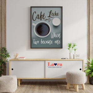 May include: A framed print with a blue background and white text that reads "Cafe Leche con When two become one". The print features a cup of coffee and a small pitcher of milk. The print is hanging on a white wall above a wooden cabinet.