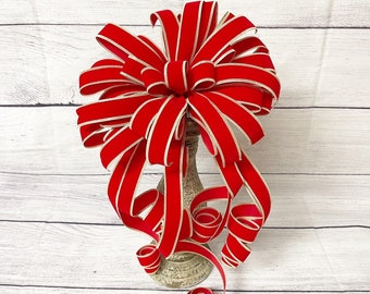 May include: A large red velvet bow with gold trim, tied on a decorative stand. The bow is ideal for adding a festive touch to any Christmas decor.