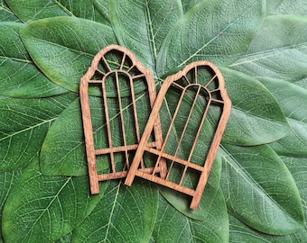 May include: Two wooden decorative arches with a lattice design. The arches are brown and have a rustic look. They are set against a backdrop of green leaves.
