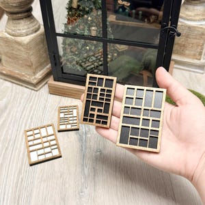 May include: Several miniature wooden window frames with geometric designs. The frames are in various sizes, with a mix of light and dark wood. One frame is held in a hand, showcasing the intricate details of the design.