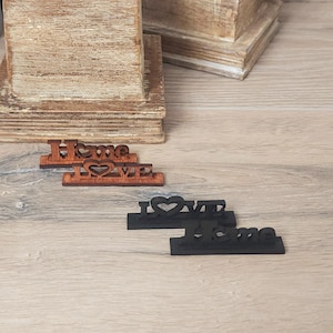 May include: Two wooden signs with the words "Home" and "Love" with a heart cutout, and two black signs with the words "Love" and "Home" with a heart cutout.