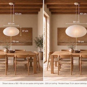 May include: Two white oval paper pendant lights hanging over a wooden dining table. The left light measures 60 cm wide by 37 cm high, and the right light measures 80 cm wide by 49 cm high. Both are positioned 75 cm above the table surface.