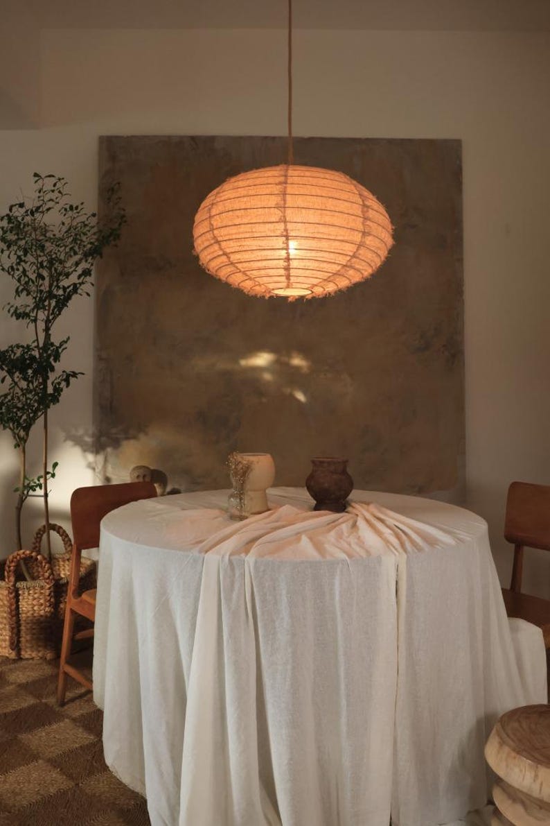 Taupe linen dome pendant light shade with soft rounded silhouette, hanging ceiling lamp cover in neutral fabric, creating a warm diffused glow. Elegant oversized dome design suitable for dining room, bedroom, or living space. Natural linen texture adds depth and calm ambiance, with optional fringed or clean edge finish for modern or classic interior styling.