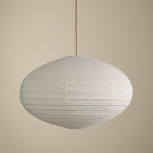 May include: A white oval-shaped paper lantern pendant light with a ribbed texture, suspended from a thin brown cord. The light fixture features a delicate, lightweight paper shade that creates a soft, rounded silhouette against a neutral background.