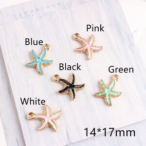 Pode incluir: Seis pingentes de estrela do mar dourados com pintura de esmalte em diferentes cores: azul, rosa, preto, verde e branco. Cada pingente mede 14 mm por 17 mm.