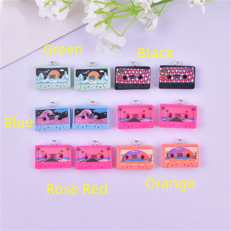 May include: Twelve colorful cassette tape charms with different designs, including palm trees, waves, and mountains. The charms are arranged in three rows of four, with each row labeled with a color: Green, Blue, Rose Red, and Orange. The charms are made of polymer clay and have a silver loop for attaching to jewelry or other crafts.