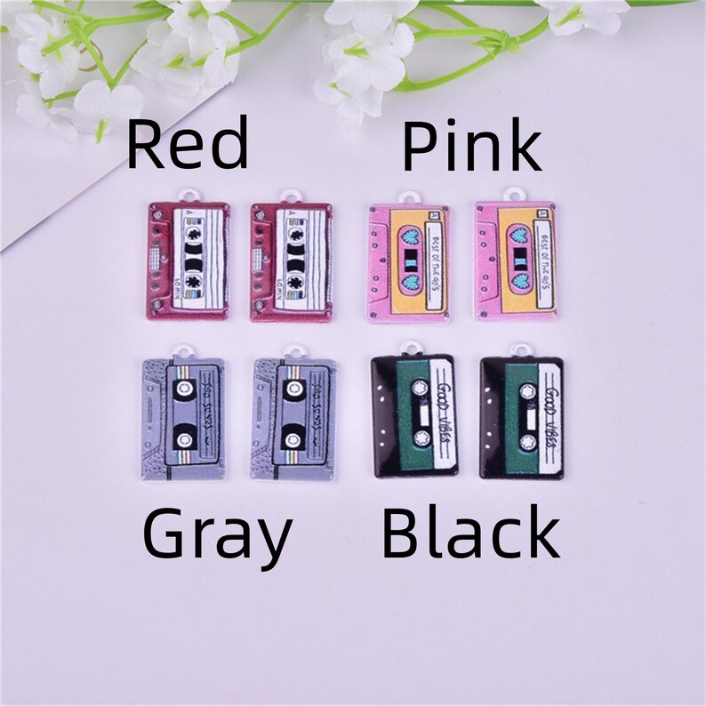 May include: Eight colorful cassette tape charms in red, pink, gray, and black. Each charm features a different design, including the text "Best of the 80's" and "Good Vibes".