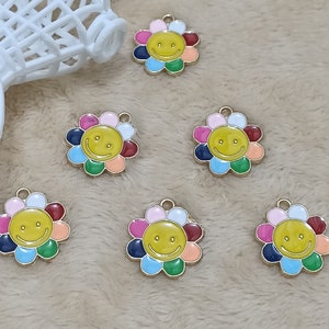 May include: Six gold-coloured flower charms with a smiley face in the centre. Each flower has six petals in different colours, including pink, blue, green, yellow, and orange.