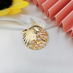 May include: Gold-tone seashell charm featuring a starfish and faux pearls. The charm has a loop at the top for attaching to a necklace or bracelet.