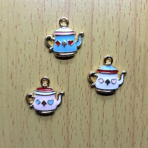 以下が含まれることがあります： エナメル塗料でできた金色のティーポットチャームが3つ。ティーポットはトランプのシンボルとハートで飾られています。ティーポットは青、白、ピンクです。