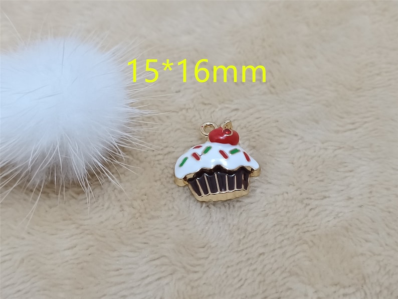May include: Gold cupcake charm with white frosting and red and green sprinkles. The charm is 15mm by 16mm.